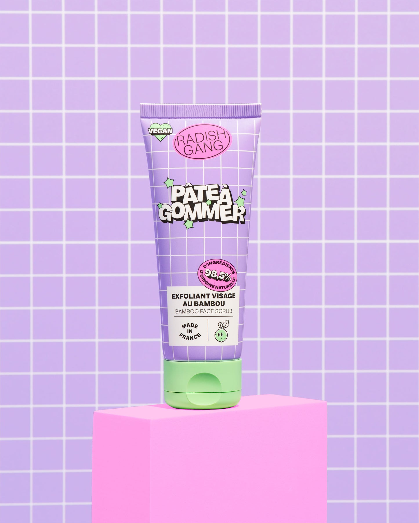 Tube du gommage présenté sur un socle avec un fond coloré et quadrillé